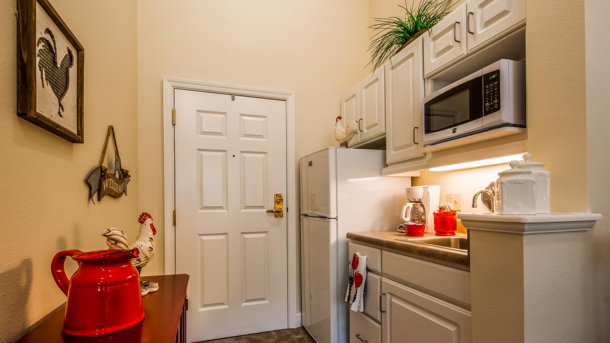 A compact kitchen area with white cabinets, a microwave, and a refrigerator.