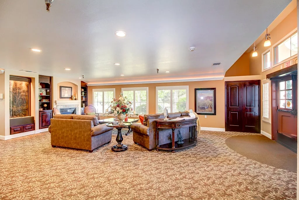 A spacious and bright living room with comfortable sofas, a central table, and large windows.