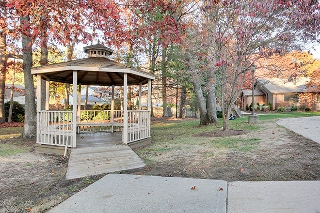 A scenic view of a gazebo surrounded by autumn foliage in a park setting.