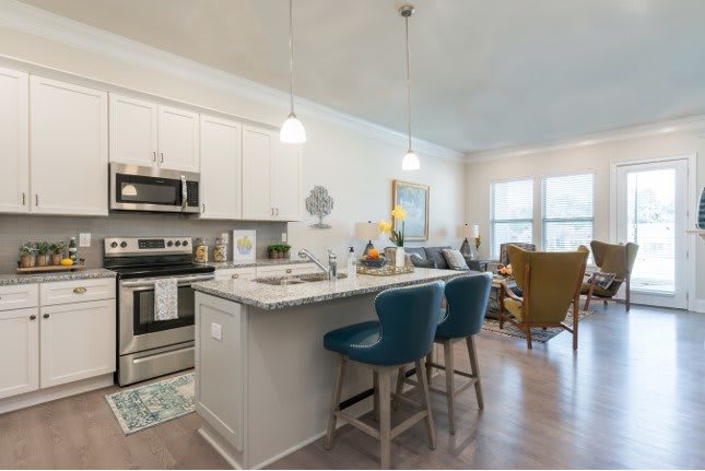 Modern open floor plan featuring a stylish kitchen with an island, bar stools, and stainless steel appliances adjacent to a cozy living area.