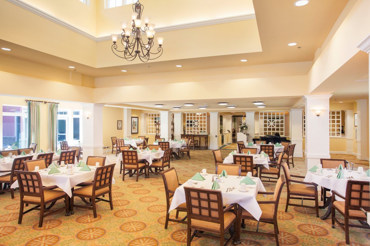 An elegant dining room with neatly arranged tables and a chandelier.
