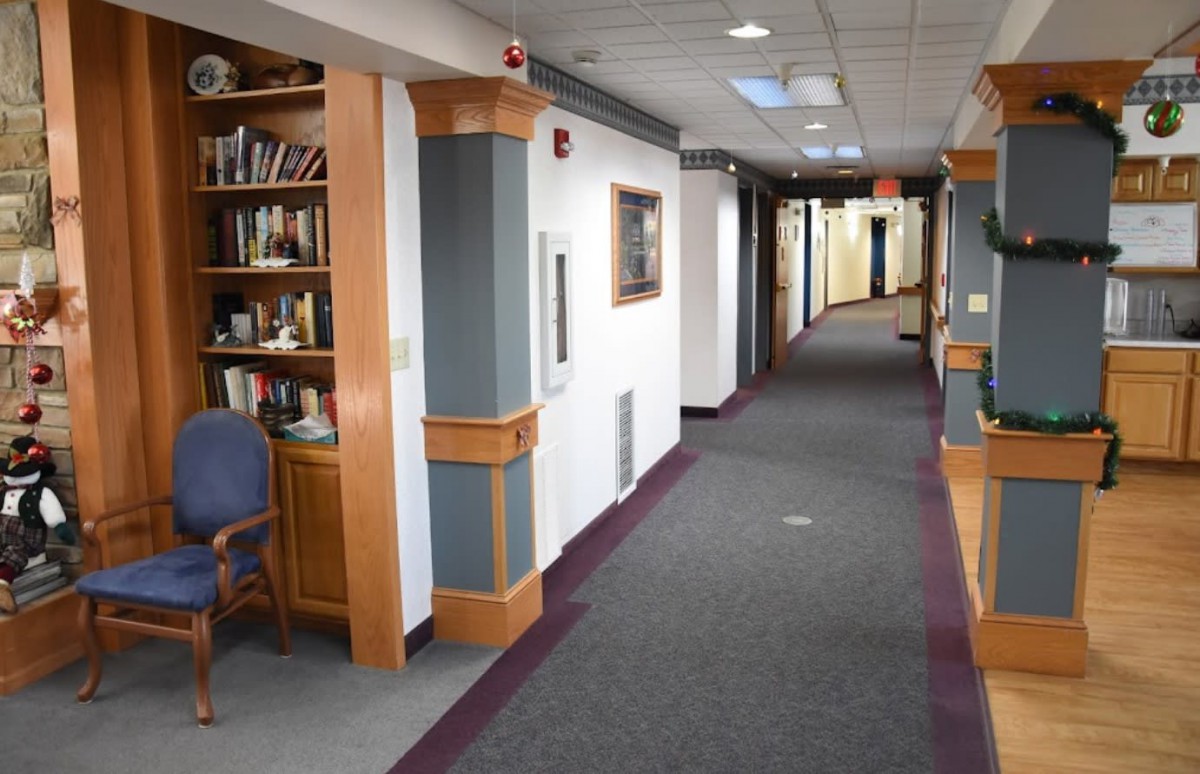A quiet office hallway with carpeted floors and bookshelves lining the walls.