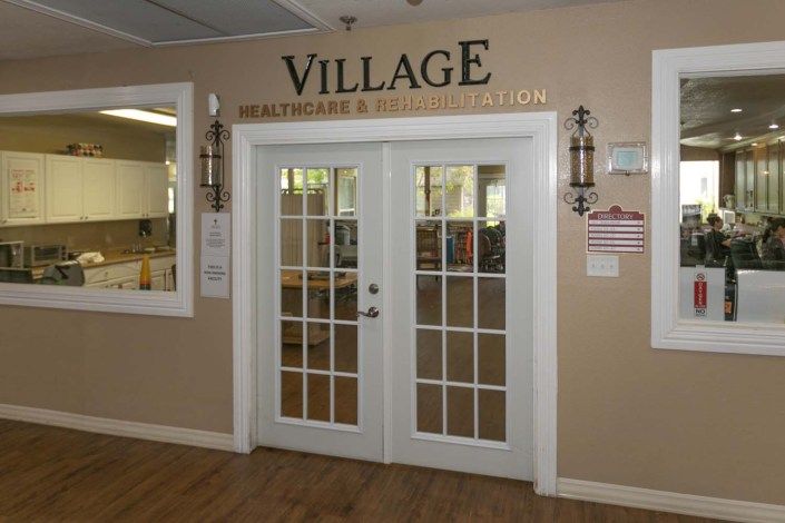 Entrance to the Village Health Care and Rehabilitation center with glass double doors.