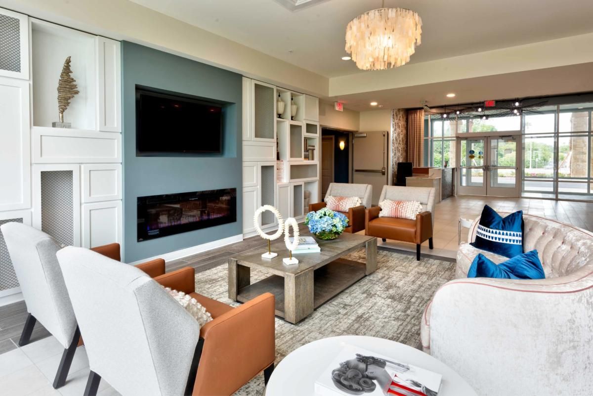 A modern living room featuring a comfortable seating area with a coffee table, wall-mounted TV, and a stylish chandelier.