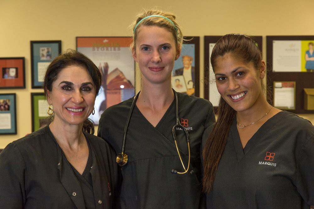 Three medical professionals smiling while wearing uniforms.