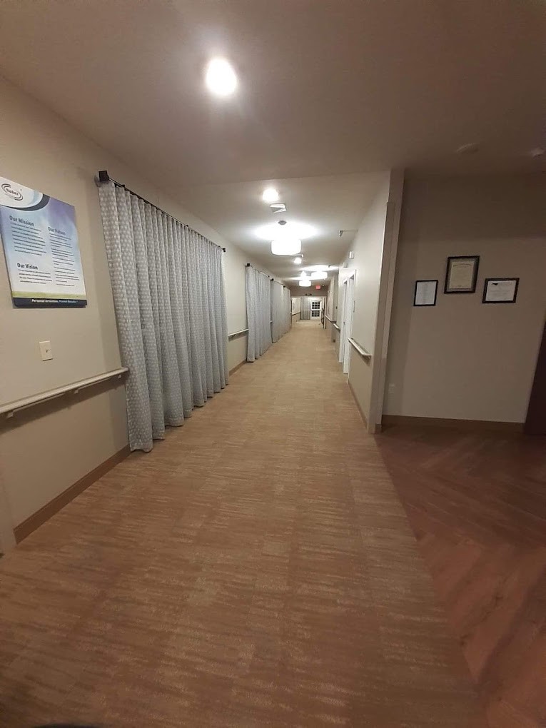 A long hospital corridor with linoleum flooring and curtains along the walls.