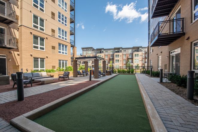 A modern apartment complex with a spacious courtyard featuring a green space and seating areas.