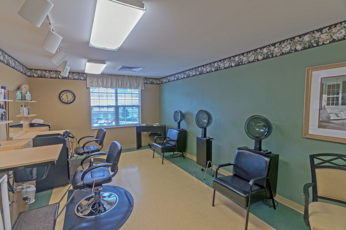 An empty hair salon with chairs and hair dryers arranged neatly.