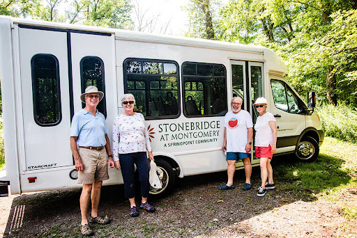 A cheerful group posing in front of the Stonebridge bus during a scenic outing.