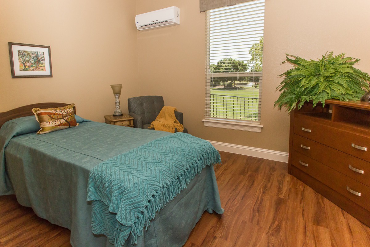 A cozy bedroom with a single bed and natural lighting through the window.