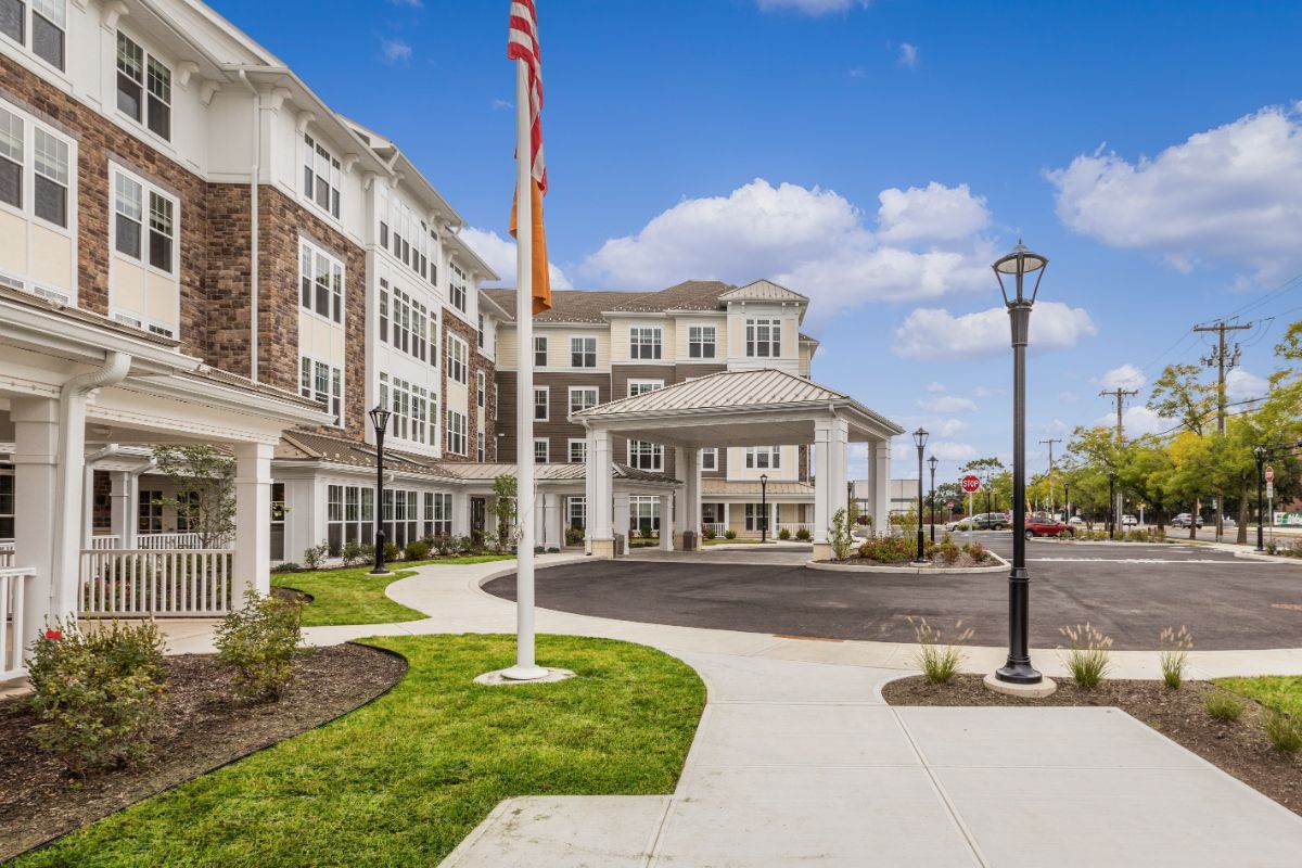 A modern residential building with a flagpole and landscaped surroundings on a clear day.