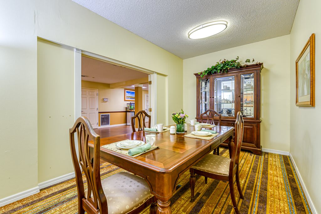 A warmly decorated dining room with a wooden table and chairs, complemented by a china cabinet.