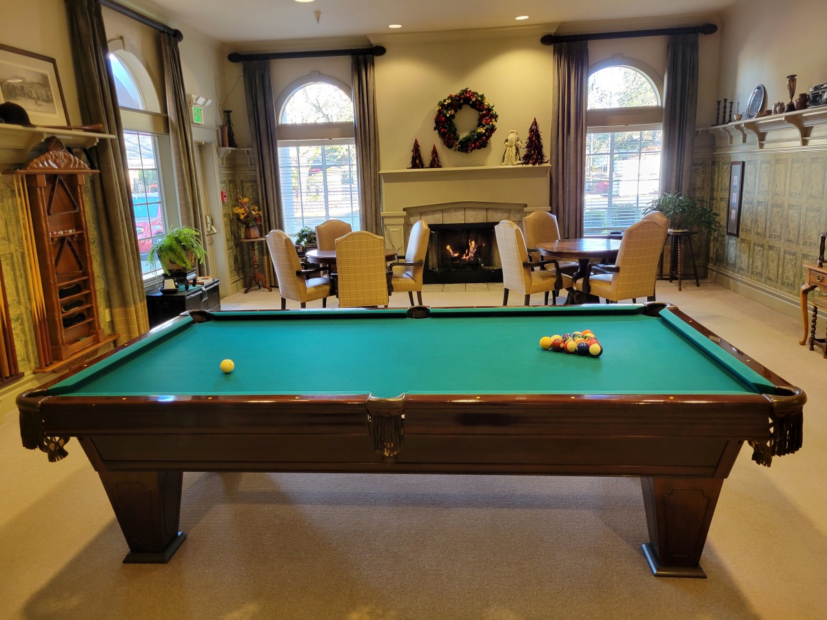A cozy game room featuring a pool table and a fireplace, with seating arrangements for relaxation.