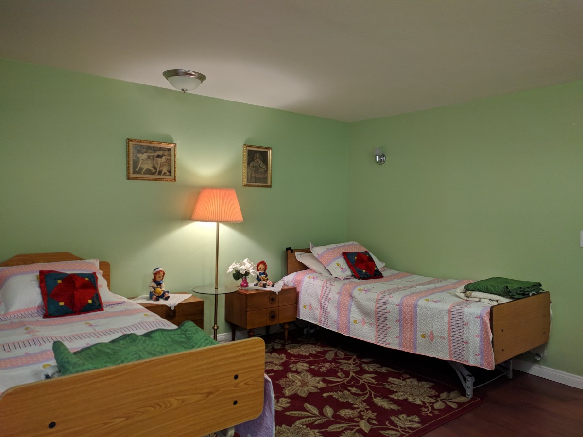 A cozy bedroom with twin beds, a lamp, and decorative wall art.