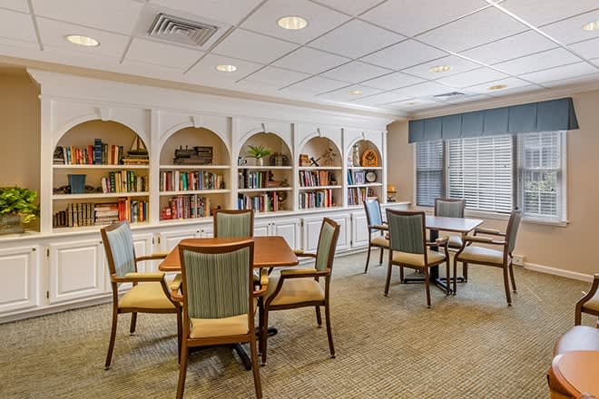 A cozy library with bookshelves, tables, and chairs arranged for reading.