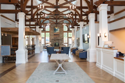 An elegantly designed lobby with high wooden beams, white columns, and a cozy stone fireplace.