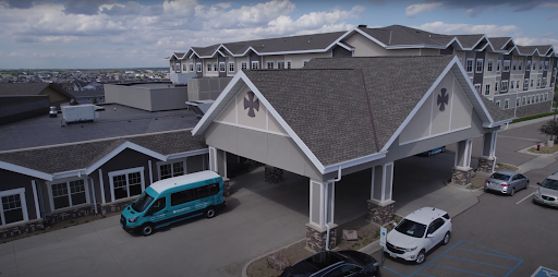A view of a modern building with a welcoming entrance and parked vehicles.
