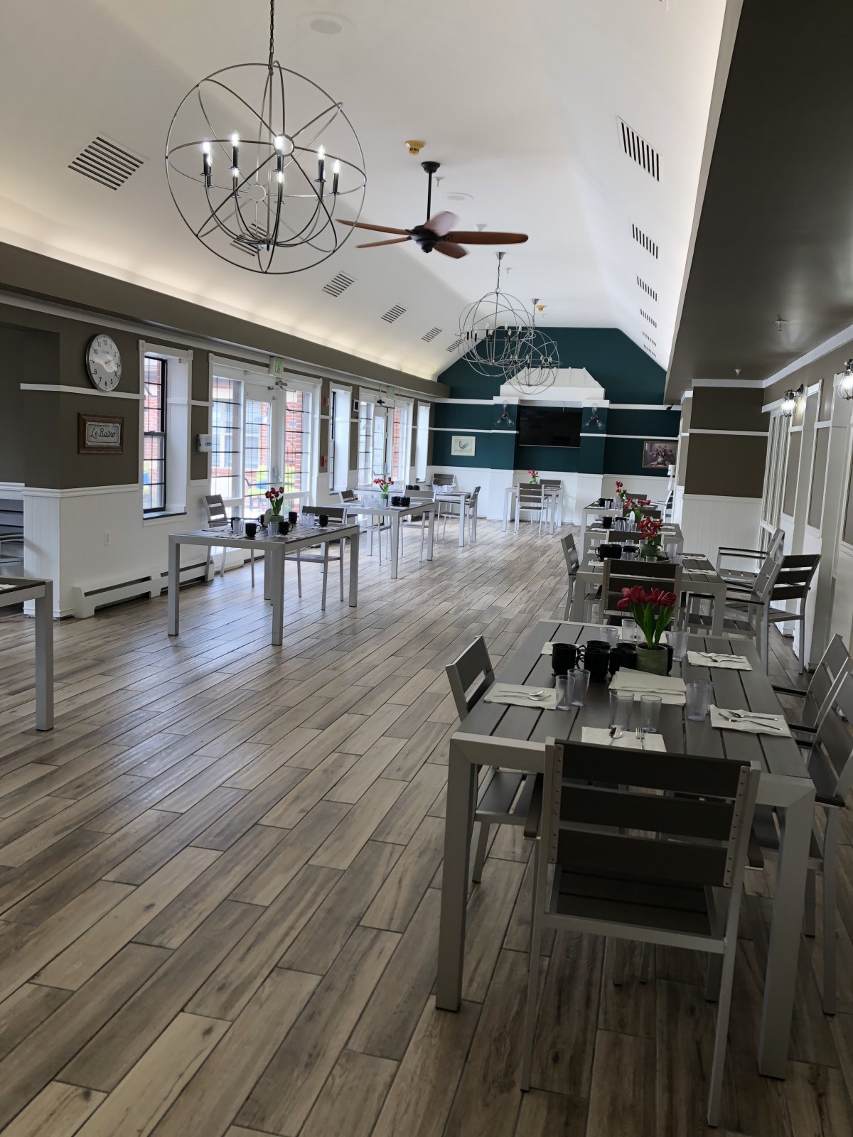 A spacious, modern dining area with sleek tables and chairs, featuring wooden flooring and large windows.