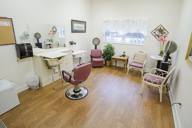 A cozy hair salon with styling chairs, a sink, mirrors, and a small waiting area.