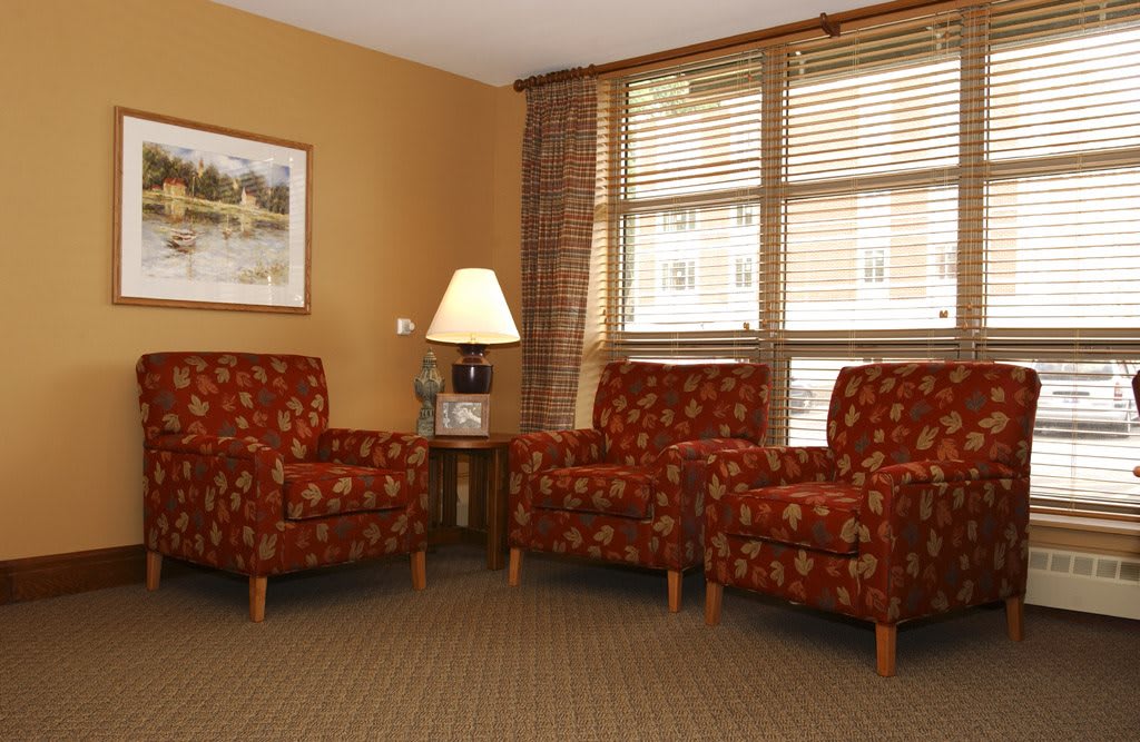 A cozy living room with patterned chairs and a lamp by the window.