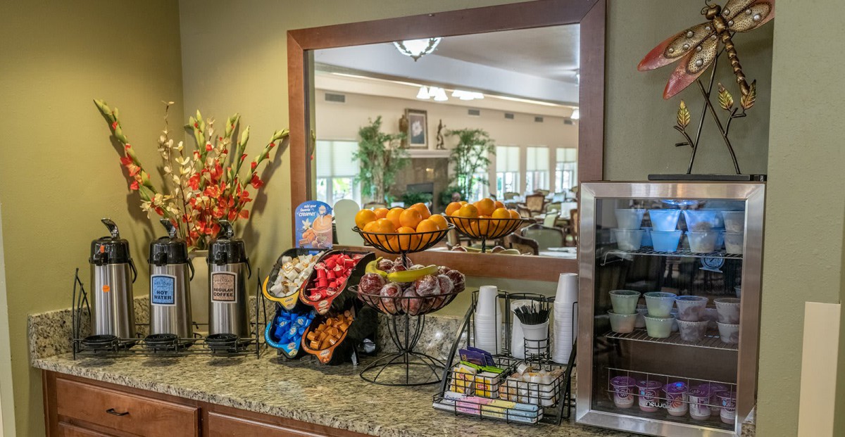 A well-stocked breakfast area with fruit, snacks, and beverages displayed on a counter.