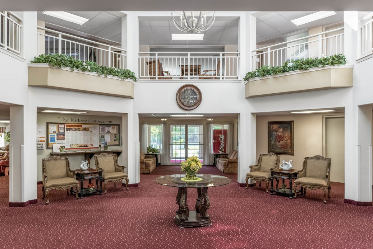 A spacious and elegantly decorated lobby with comfortable seating, a central table, and a chandelier.