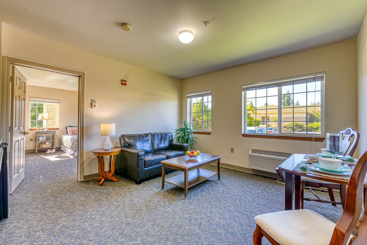 A cozy living room with a sofa, coffee table, and ample natural light.