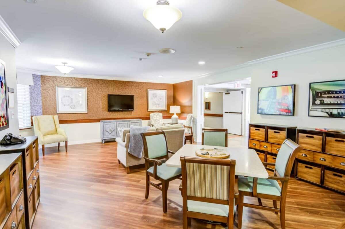 A cozy living area with seating and a television, featuring wooden floors and decorative wall art.