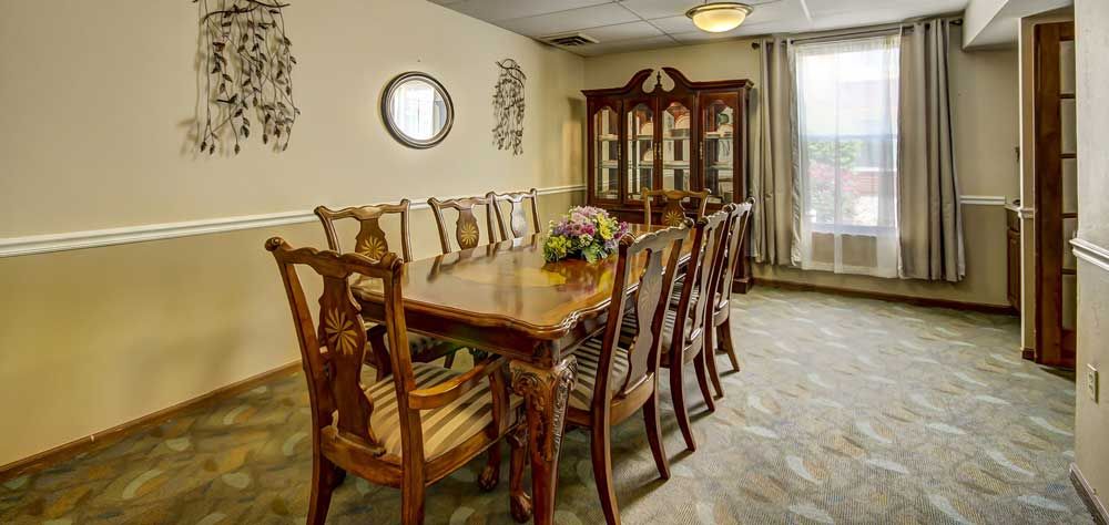 A traditional dining room with a large wooden table, matching chairs, and a decorative cabinet.