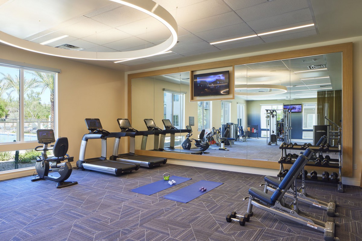 A modern gym with treadmills, exercise mats, and weights in a spacious indoor setting.