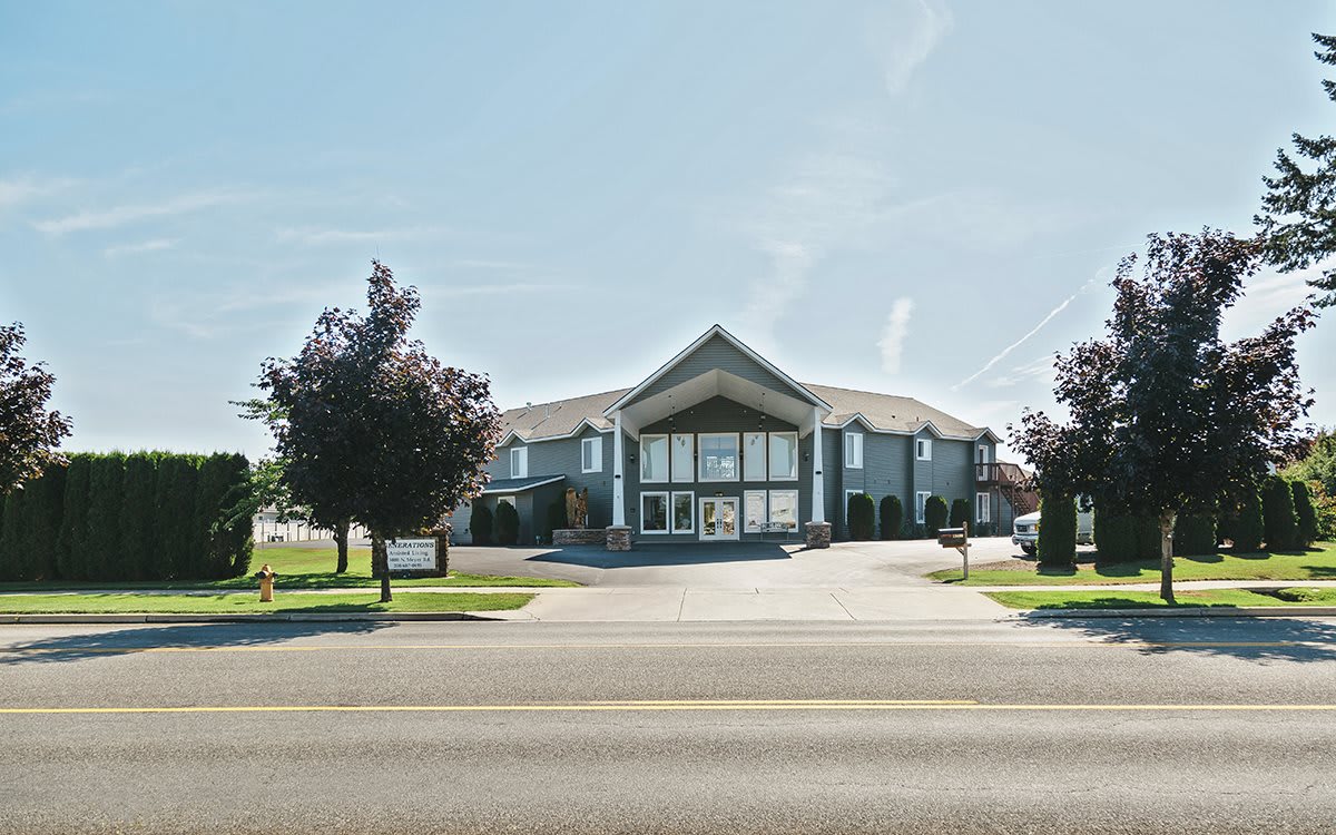 A modern office building situated along a main road with surrounding trees.