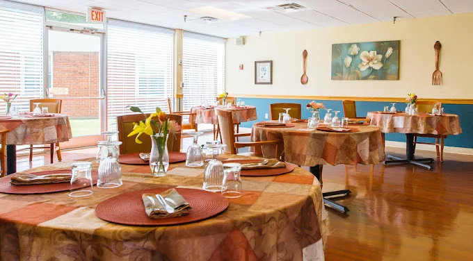 A cozy restaurant dining area with neatly set tables, featuring flowers and tableware.