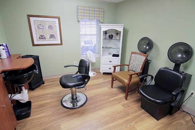 A cozy salon room featuring styling chairs, a hair dryer, and a cabinet for supplies.