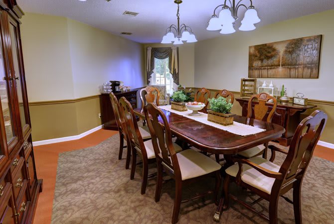 A well-decorated dining room with a wooden table and chairs, featuring elegant lighting and greenery.