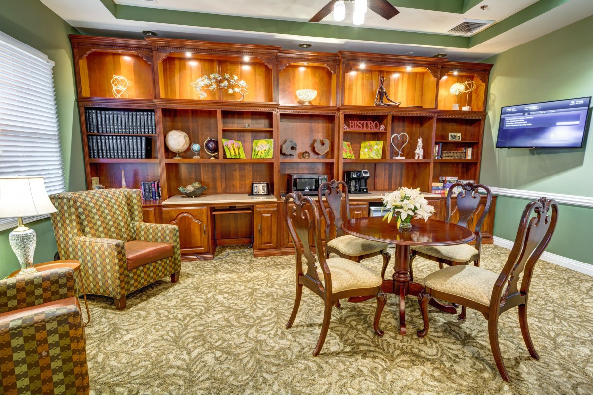 A cozy library room with wooden shelves, a round table, and an armchair.