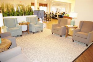 A cozy living room with several armchairs and tables arranged around a neutral-toned carpet.