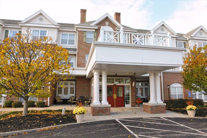 A three-story brick building with a prominent entrance featuring white columns, surrounded by landscaping.