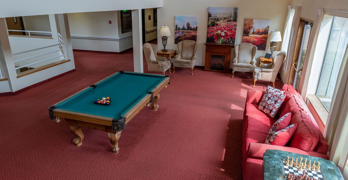 A cozy game room featuring a pool table and seating area with red carpeting.