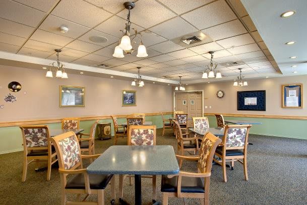 A well-lit dining area with multiple tables and chairs, featuring a cozy interior design.