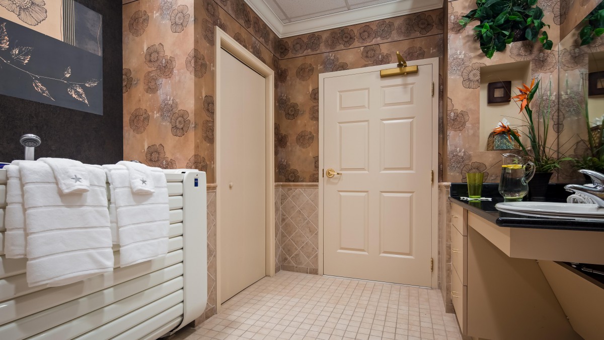 A bathroom interior featuring two closed doors, a radiator with a towel rack, and tiled flooring.