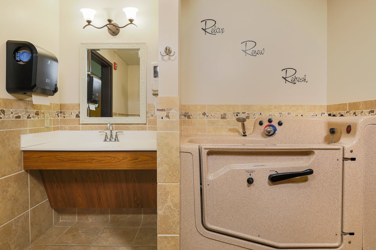 A bathroom featuring a sink with mirror and a walk-in bathtub.