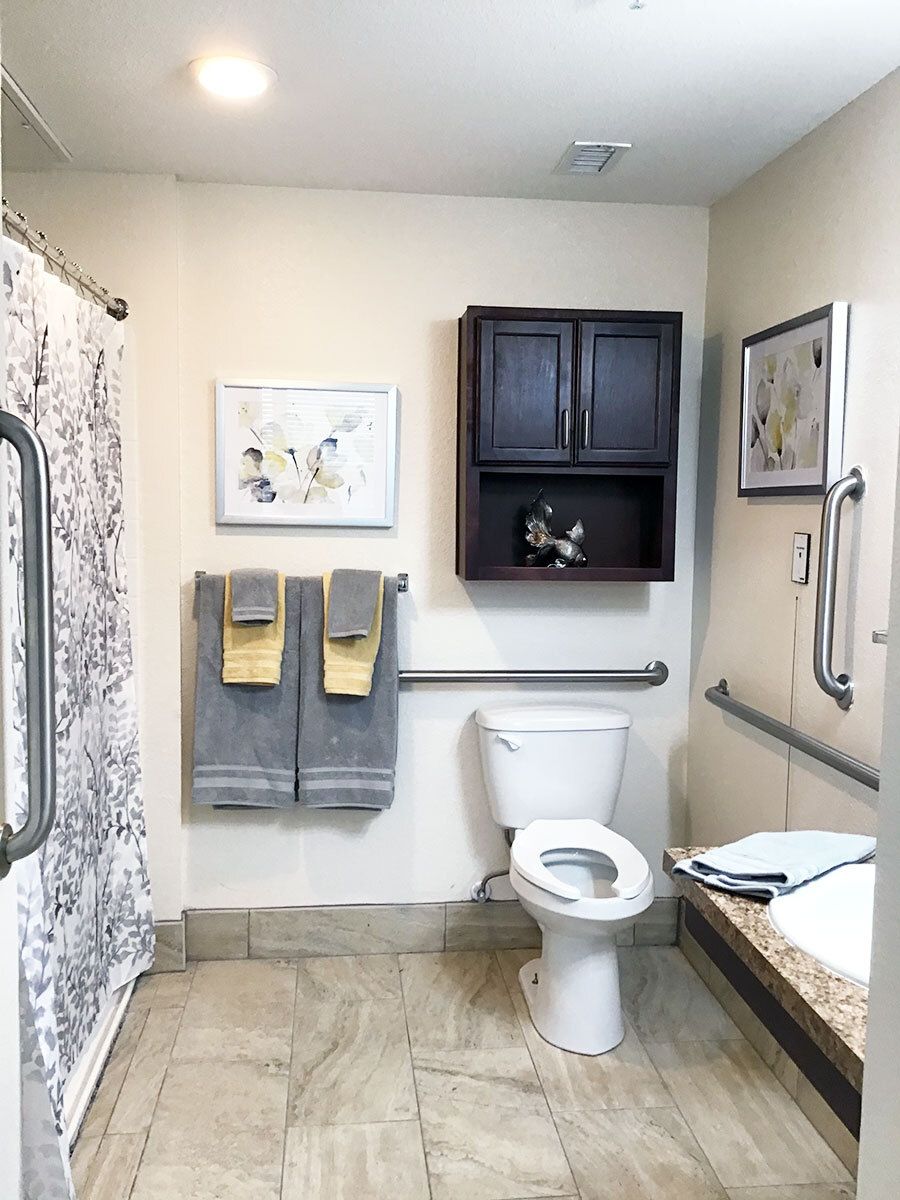 An accessible bathroom with handrails and neatly arranged towels.