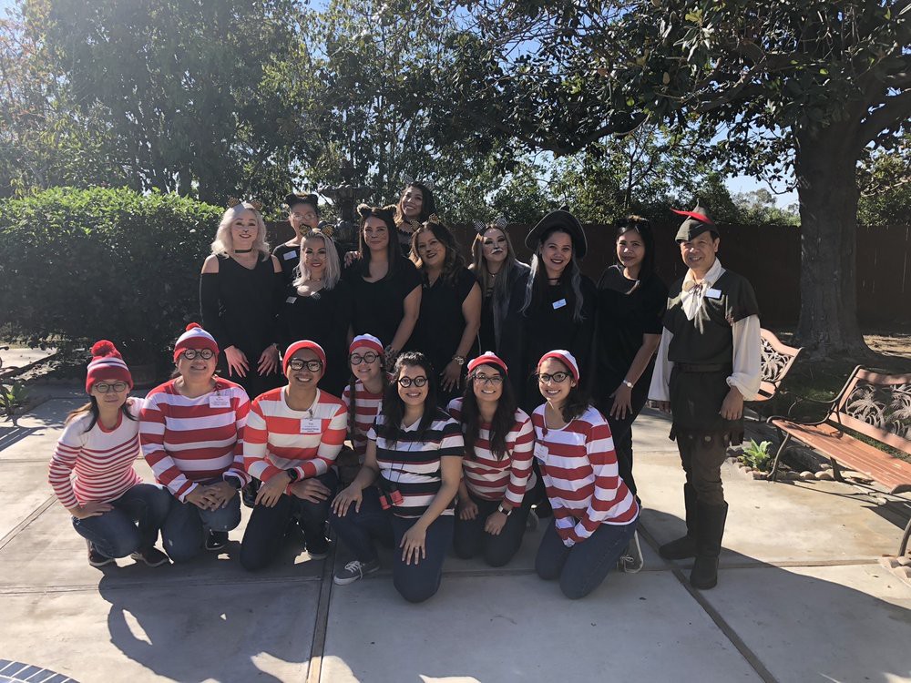 A group of people dressed in costumes, including striped shirts, gathered outdoors.
