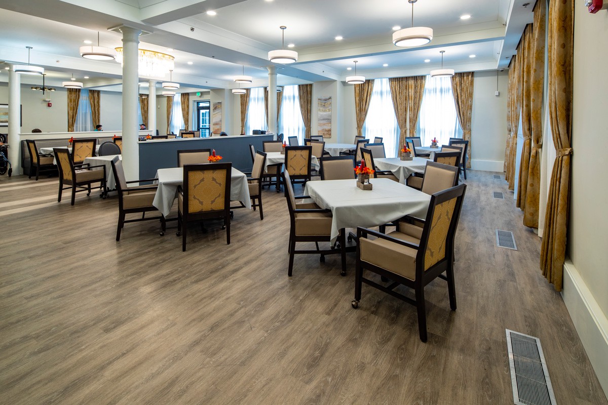 An elegant dining room with neatly arranged tables and chairs, adorned with decorative curtains and warm lighting.