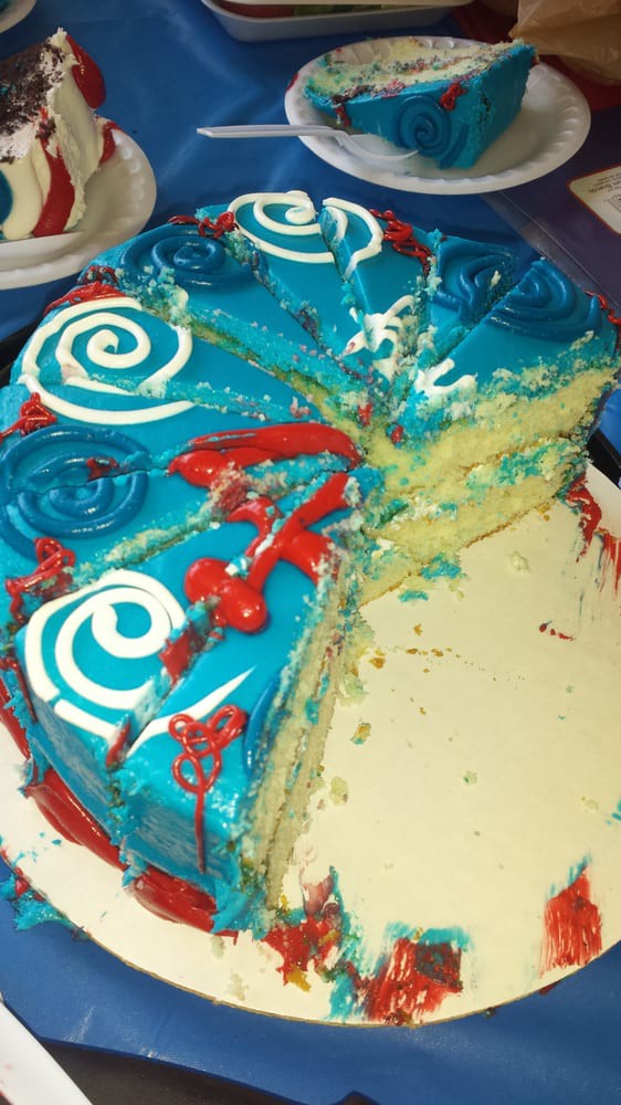 A colorful cake with blue frosting and decorative swirls, partially sliced.