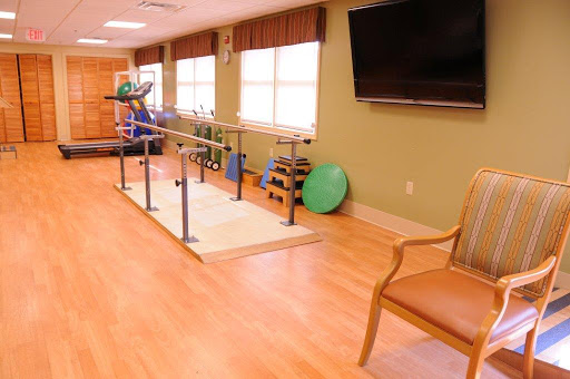 A well-equipped physical therapy room featuring parallel bars and various exercise tools for rehabilitation.