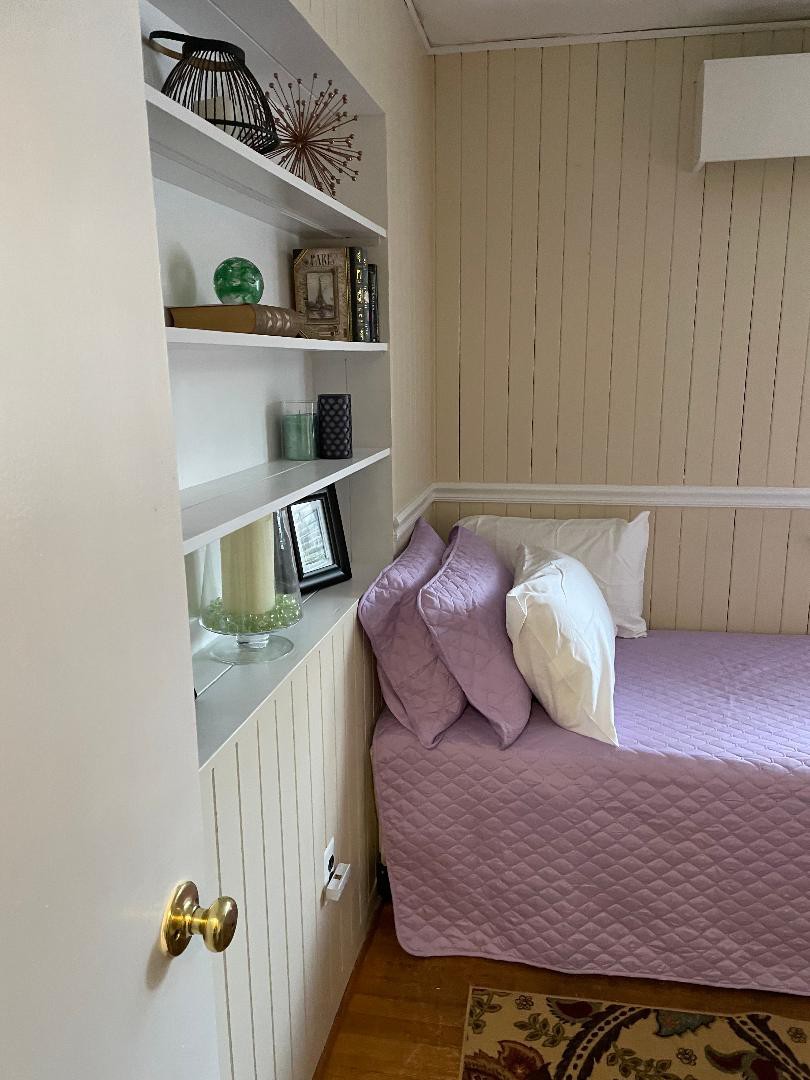 A cozy bedroom corner with built-in shelves and pastel bedding.