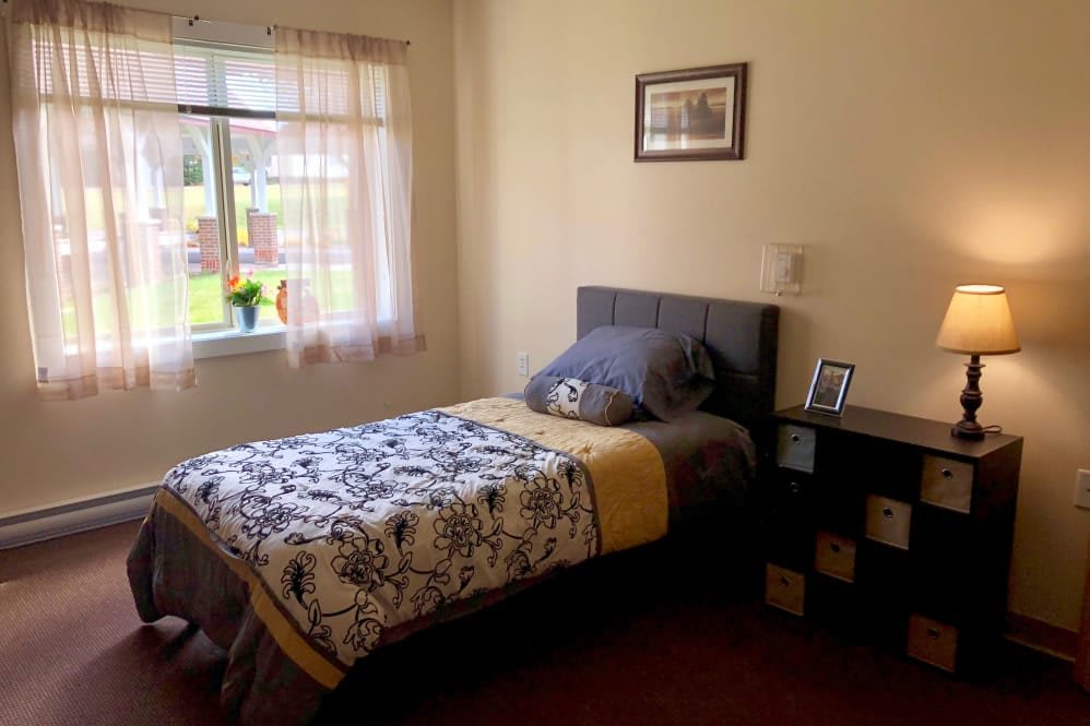 A cozy bedroom with a single bed, decorative bedding, and a window bringing in natural light.