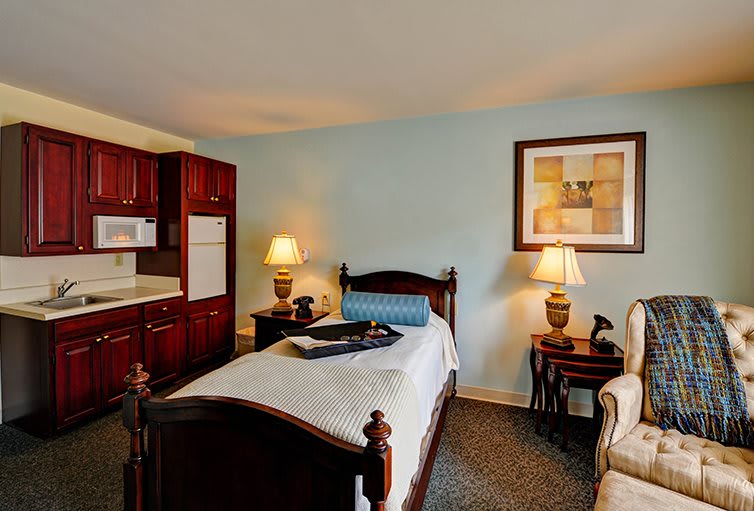 Cozy bedroom with a wooden bed, kitchenette, and warm lighting.