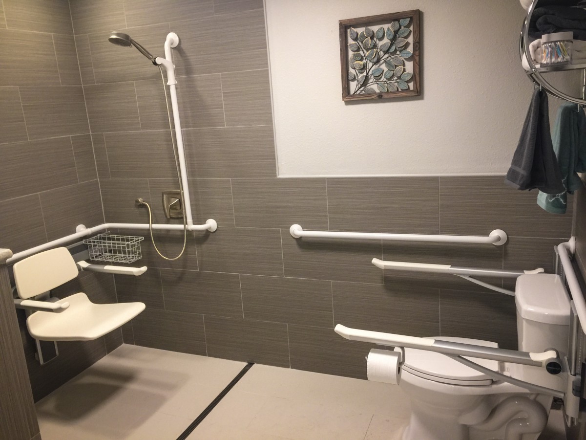 An accessible bathroom equipped with grab bars and a shower, designed for wheelchair access.